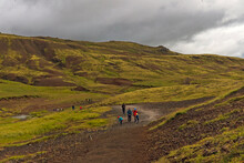 Tourists Hike Through Mossy And Wetland Terrain Of Reykjadalur Valley, Iceland. Valley Is Known For Its Mudpots, Soda Springs And Geothermal Activity.