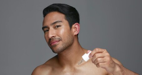 Canvas Print - Man, face and essential oil for beauty, skincare and cosmetics product on a gray, studio background. Young asian person in portrait with facial serum, dermatology dropper or collagen for skin care