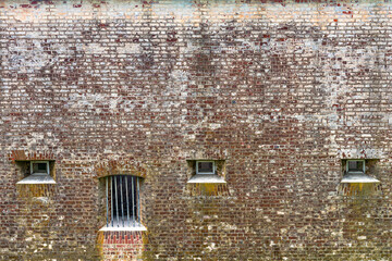 Wall Mural - Brick wall with windows and bars. A fragment of a prison wall as a background.