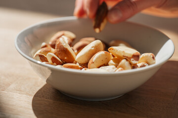 Wall Mural - Brazil nuts.hand takes brazil nuts from a plate.Healthy fats.Brazil nuts in the diet.Nuts and seeds. healthy snack.