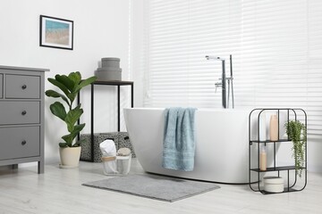 Poster - Stylish bathroom interior with bath tub, houseplants and soft light grey mat
