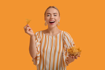 Wall Mural - Pretty young woman with nachos on orange background