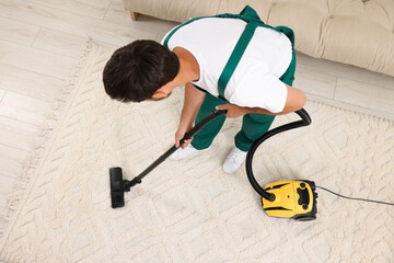 Poster - Dry cleaner's employee hoovering carpet with vacuum cleaner indoors, above view