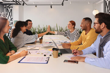 Canvas Print - Team of employees working together at table in office. Startup project