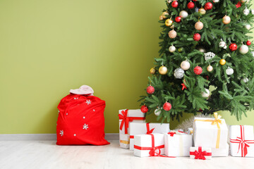 Wall Mural - Christmas tree with gifts and Santa bag near green wall in room