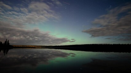 Wall Mural - evening time lapse video of a starry night with clouds moving over a very calm lake. green aurora wi