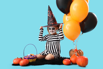 Poster - Little girl dressed for Halloween with candies and balloons on blue background