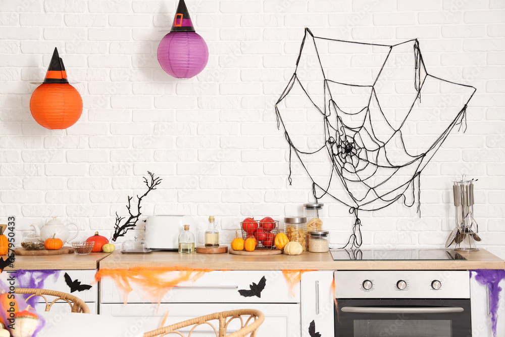 Interior of light kitchen decorated for Halloween with counters and pumpkins