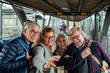 © Marko Geber - Group of senior friends taking selfies on a smartphone at the train station