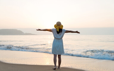 Wall Mural - Happy woman standing on the beach with arms outstretched.