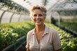 © Naveen - Portrait of a mature woman in a green house,  surrounded by rows of vibrant green plants.