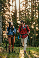 Wall Mural - A couple clad in professional hiking gear makes their way through a mystical forest in pursuit of outdoor adventure