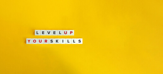 Wall Mural - level up your skills phrase and concept image. letter tiles on yellow background. minimal aesthetic.