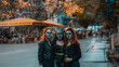 Dia De Los Muertos (Day of the Dead) Women with Painted Black and White Faces standing next to each other on a street during fall November 1 with yellow and orange leaves and girls backlit orange hair