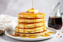 a stack of fluffy pancakes with maple syrup drizzle