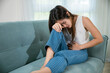 © sorapop - Asian young woman unhappy closing eyes with stomach ache on sofa in living room, female pain lying on couch at home, suffering from strong abdominal painful colon problem feeling unwell