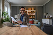 © Moon Safari - Cheerful elegant businessman holding document and smart phone while working at desk in home office
