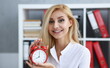 © H_Ko - Smiling business woman holding in hand on the alarm clock a red color showing eight o'clock in the morning or evening AM PM