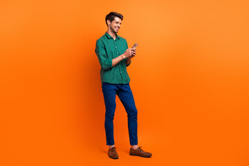 Aufkleber - Full body photo of young guy worker hr manager recruiter browsing swipe internet web pages smartphone isolated on orange color background