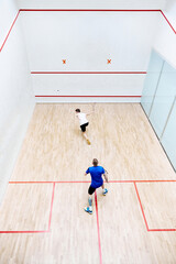 Wall Mural - Top view of two young men, friends, sportsmen playing squash on squash court. Competition. Concept of sport, hobby, healthy and active lifestyle, game, gym, ad