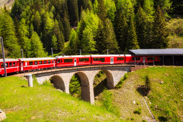 Wall Mural - Red train moving in beautiful mountain landscape in Switzerland