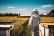 Viewed from behind, someone in a beekeeper suit stands near an array of beehives, amidst a vibrantly flowering field, illustrating a tranquil moment in apicultural practice.