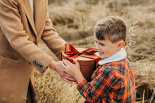 Mother Giving Gift Box To Happy Son In Field