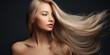 a beautiful woman blowing her long blonde hair on a grey background, concept of Beauty and hair care with keratin