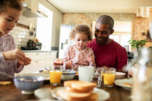 Young Father Having Breakfast With His Daughter In The Kitchen At Home