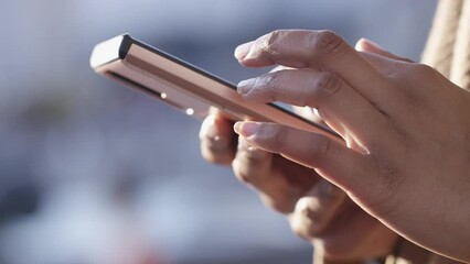 Close shot of female hands using a touch screen cell phone outdoors in the city 