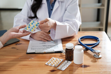 Wall Mural - Female doctor giving pills bottle to male patient in clinic. Concept of healthcare, medical treatment and insurance.