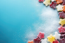 Frame Of Different Colors Of Jelly Or Marmalade Candies In Powdered Sugar On A Blue Background. Free Space For Product Placement Or Advertising Text.