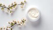 whitening and moisturizing Face cream in an open glass jar and flowers on white background. Set for spa, skin care and body products and solutions for skin problems such as scars, acne, wrinkles.