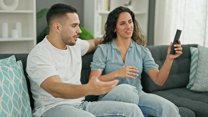 Wall Mural - Man and woman couple fighting for tv remote control at home