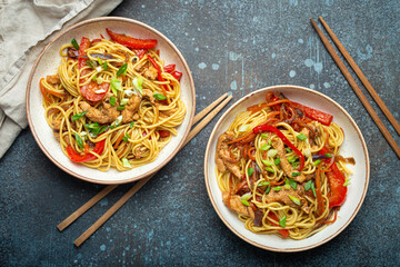 Canvas Print - Two bowls with Chow Mein or Lo Mein, traditional Chinese stir fry noodles with meat and vegetables, served with chopsticks top view on rustic blue concrete background.