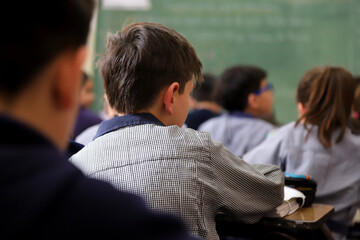 Primary school students in classes. Students in class at a Catholic school. Boys at their desks dressed in uniform. Education. Children learning at school.