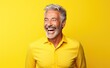 © steffenak - Photo of older male smiling and laughing on bright yellow background