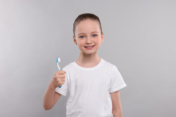 Wall Mural - Happy girl holding toothbrush on light grey background