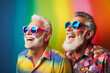 Happy old LGBT male gay couple wearing colourful clothes and sunglasses