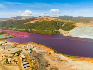 Open pit nickel mining and dark red polluted lake. Mindanao, Philippines.