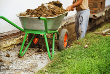 Worker With Full Wheelbarrow On Construction Site