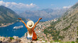 © M.studio - Rear view of woman with open arms enjoying panoramic view of Kotor Bay- travel, tour tourism, vacation in Montenegro, Europe