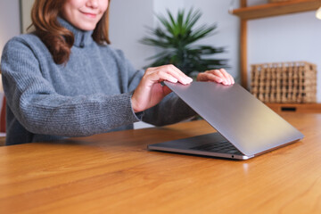 Wall Mural - closeup image of a woman close and open a laptop computer on table after finished using it
