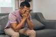 © NanSan - Middle-aged Asian Indian man with psychosis, depression, headache, migraine, sitting on sofa.
