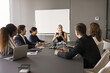 © fizkes - Confident middle aged team leader woman meeting with diverse group in boardroom, talking to employees, discussing work tasks, plan, strategy. Corporate teacher giving seminar to staff