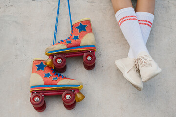 The concept of roller skating and active recreation. Close-up of vintage rollers and legs of a teenage girl. A teenage girl rests after rollerblading.