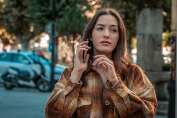 Wall Mural - thoughtful young woman with phone on the street