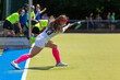Young female field hockey player performing short corner