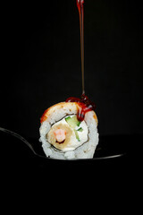 Wall Mural - Sushi rolls are doused with soy sauce on a dark background