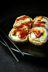 Wall Mural - Sushi rolls in a dark plate on a black background